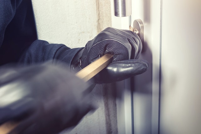 person in black gloves prying a door open